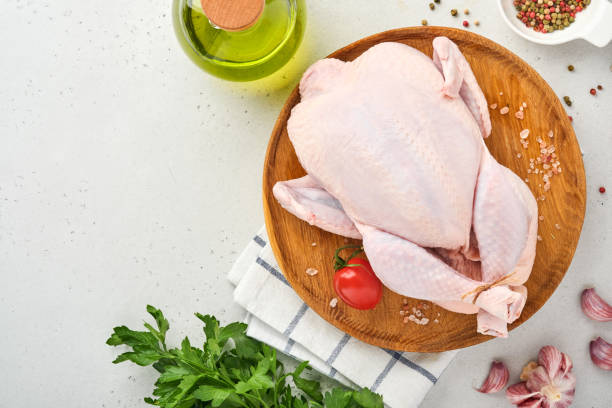 istock Whole raw chicken with ingredients for making rose pepper, lemon, thyme, garlic, cherry tomato, sorrel and salt in the kitchen on light grey slate, stone or concrete background. Top view. copy space 1341470433