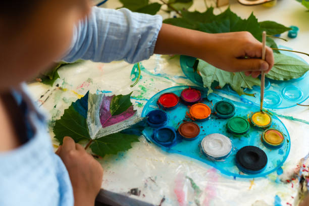 istock two schoolgirls paint the leaves 1341470660