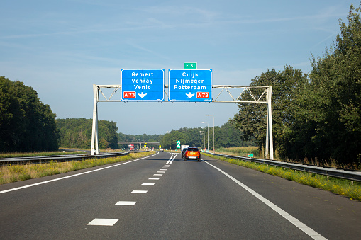 Cujk, The Netherlands - September 06, 2021: Traffic on Dutch rijksweg A 73 nearby Cuijk. The A73 motorway (Dutch: Rijksweg 73) is a motorway in the Netherlands. It connects the A50 at the Ewijk interchange in Beuningen with the cities of Venlo and Roermond. Some road users in the background.
