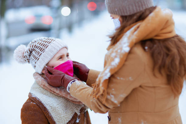 maman et enfant à l’extérieur en ville en hiver portant un masque médical - childcare centre photos et images de collection