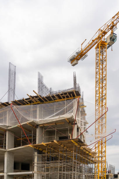 istock Construction crane and unfinished residential building against grey sky. Housing construction, apartment block with scaffolding 1341475249