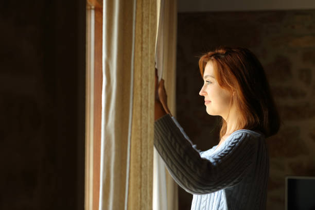 istock Satisfied woman opening curtains at home 1341475682