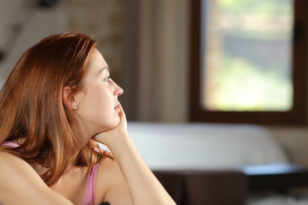 istock Woman looking through a window in the bedroom 1341475763