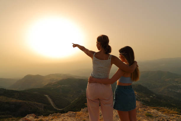 Women pointing at sunset in the mountain
