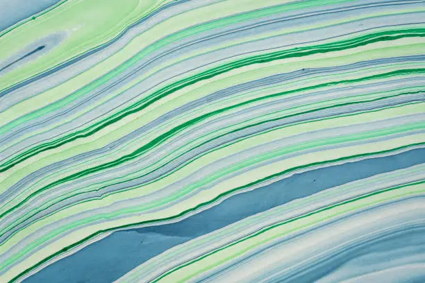 background of handmade Thai marbled mulberry paper in green and blue with flowing pattern