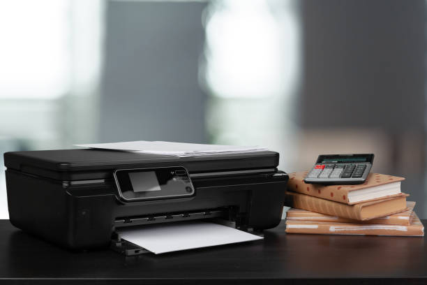 istock Stack of books and home printer against blurred background 1341477181