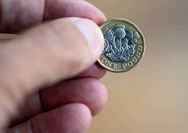 istock Man's hand holding one pound coin 1341478823
