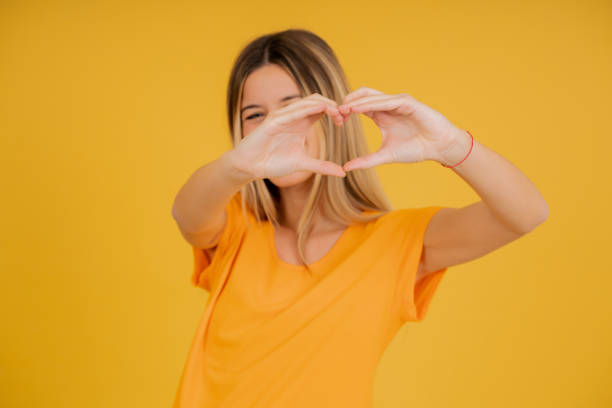 istock Young woman smiling while making a heart with her hands. 1341478921