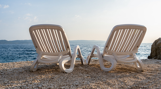 Pair Of White Adirondack Chairs On A Beautiful Beach in Croatia. Summer And Vacation concept.