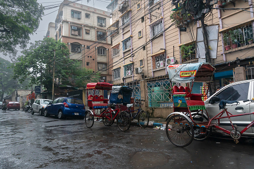 Kolkata, West Bengal, India - 4th August 2020 : Image shot through raindrops falling on wet glass, hand pulled rickshaws under rain - monsoon stock image of Kolkata (formerly Calcutta) city ,