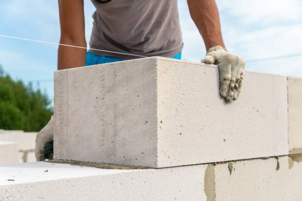 istock Builder makes a concrete wall with cement blocks on the construction site of a house. Concept of building a house 1341482849
