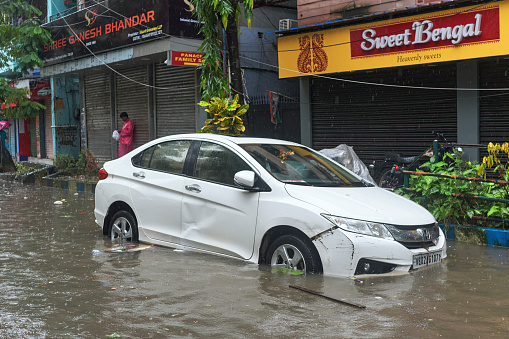 Lake Market, Kolkata, 09/20/2021: Near a closed marketplace, a car parked at roadside is stuck in rainwater, flooding the entire area. Heavy rain caused by low depression over Bay of Bengal floods several parts of city and adjoining districts causing havoc in everyday life.