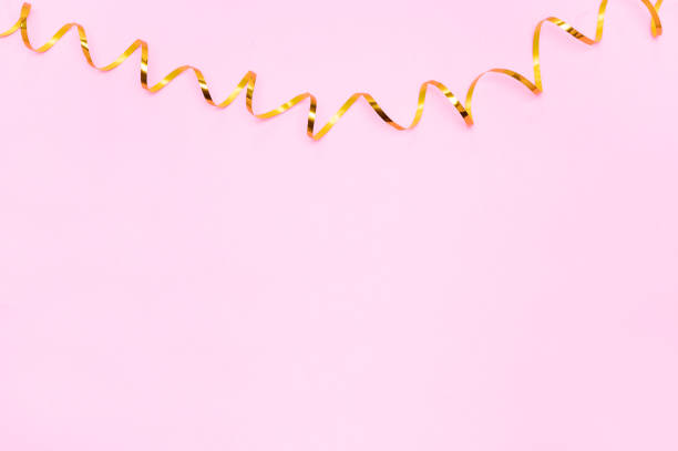 istock Golden ribbons isolated on pastel pink backgrou 1341483274