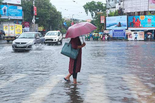 Rashbehari, Kolkata, 09/20/2021: An office going woman walking through flooded street in midst of rain caused by low depression over Bay of Bengal floods several parts of city and adjoining districts causing havoc in everyday life.