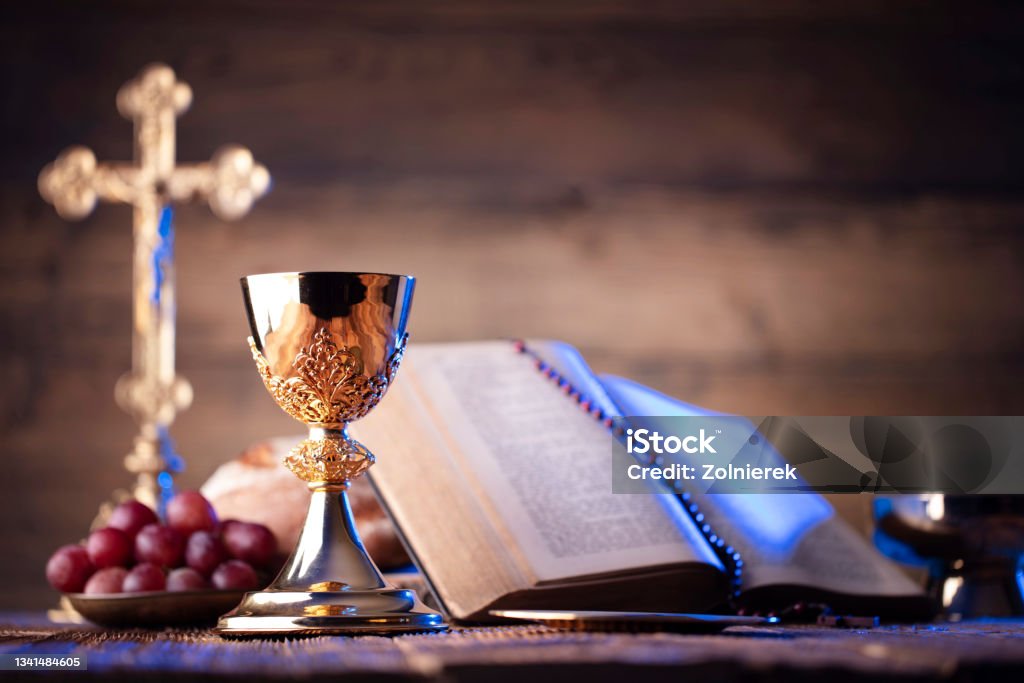 Catholic religion concept. Catholic symbols composition. The Cross, Holy Bible, rosary and golden chalice on the altar. Spirituality Stock Photo