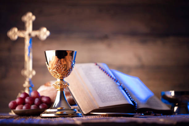 Catholic religion concept. Catholic symbols composition. The Cross, Holy Bible, rosary and golden chalice on the altar. liturgy photos stock pictures, royalty-free photos & images