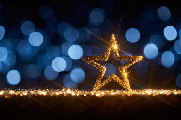 Shiny golden stars background- Christmas Star Defocused Gold Blue Bokeh Shiny golden stars, shimmering glitter and defocused lights in a yellow blue contrast. christmas star shape christmas lights blue stock pictures, royalty-free photos & images