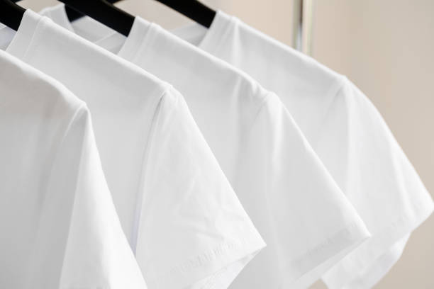 istock Row of white t-shirts on hangers on rack 1341484752