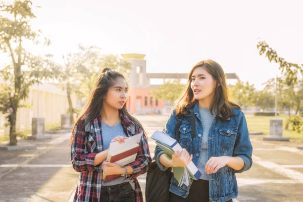 istock Two Asian female students discussing about latest content of textbook in university after learning in classroom. Life of studying and friendship concept. 1341484823