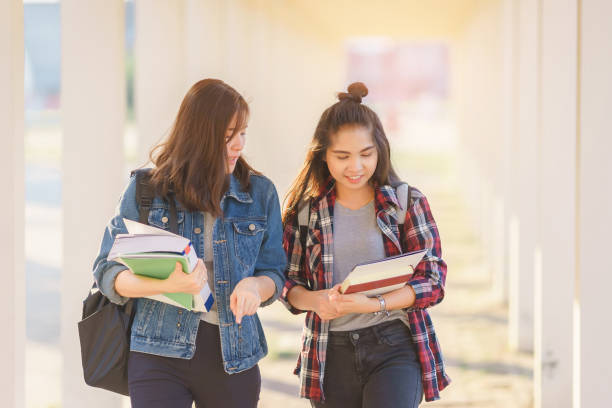 istock Two Asian female students discussing about latest content of textbook in university after learning in classroom. Life of studying and friendship concept. 1341484836