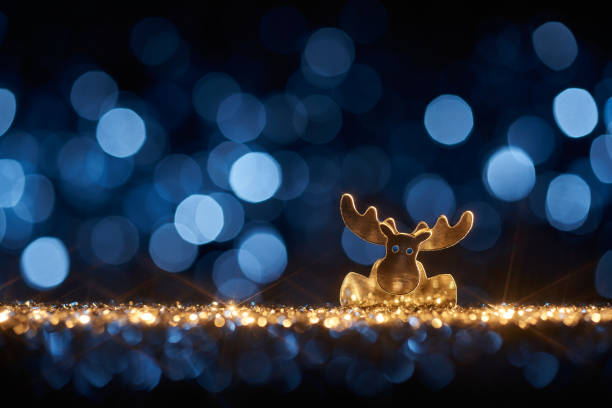 Cute Christmas reindeer on shimmering glitter, shiny stars and defocused lights in a yellow blue contrast.