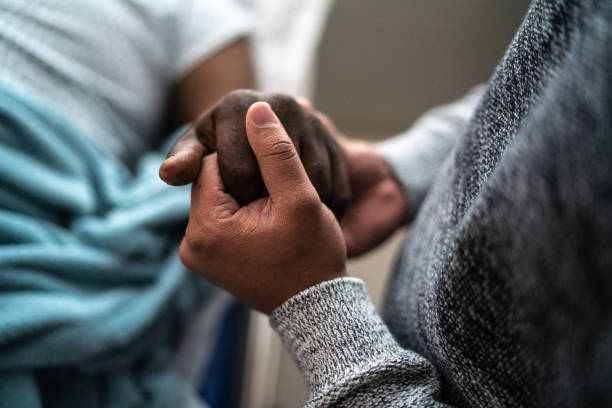 Son holding father's hand at the hospital