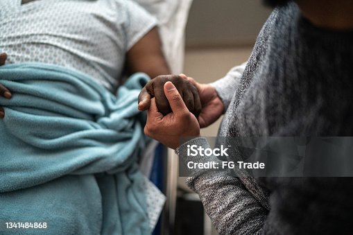 istock Son holding father's hand at the hospital 1341484868