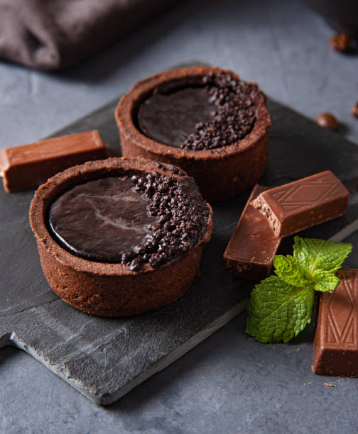 mini chocolate tarts  with piece chocolate on dark  background. Macro view