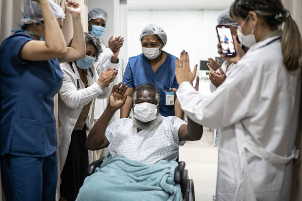 ärzte und krankenschwestern feiern älteren mann, der das krankenhaus nach der genesung verlässt - mit schutzmaske - nurse high five mask stock-fotos und bilder