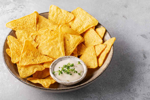 istock corn nachos in a plate with cream or garlic sauce on a gray background, horizontally 1341496215