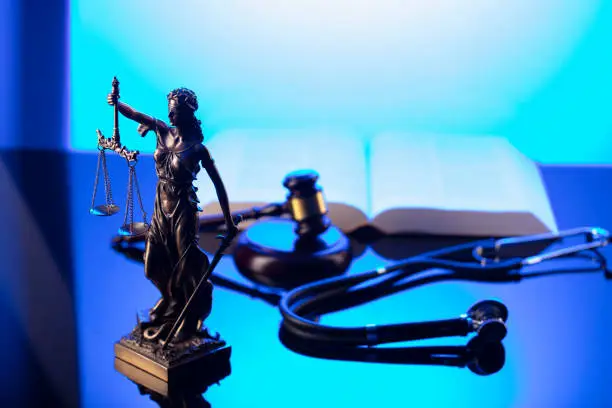 Gavel, Themis, legal code and stethoscope on the glass table. Blue light.