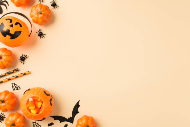 istock Top view photo of halloween decorations pumpkin baskets candy corn straws spiders web and bats silhouettes on isolated beige background with copyspace on the right 1341496821