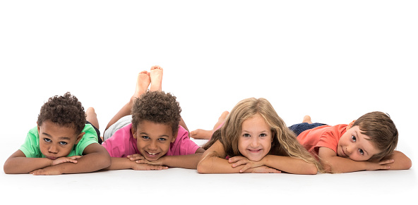 Group of happy little kids lying on the floor, isolated on white, studio shot