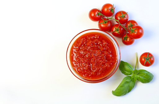 Homemade Italian tomato sauce with basil leaves on white background. Directly above.