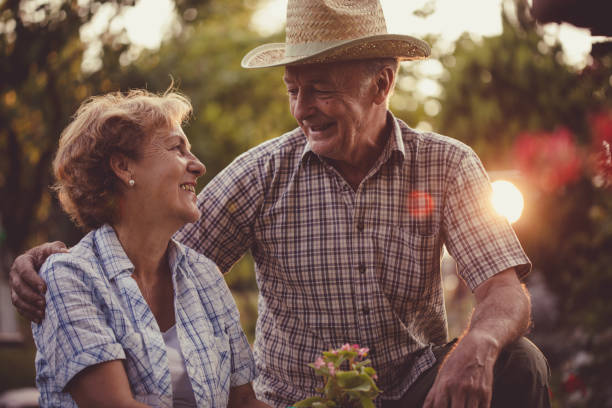 заслуженные расслабляющие годы пенсионерской пары в саду - 60 64 years стоковые фото и изображения