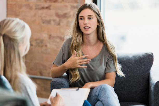 gesten der weiblichen klientin im gespräch mit einem nicht erkennbaren therapeuten - mental health professional therapy patient psychiatrist stock-fotos und bilder