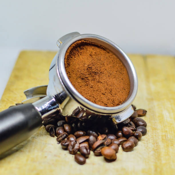 istock Fresh grounded coffee in espresso machine port filter surrounded by coffee beans. 1341506639