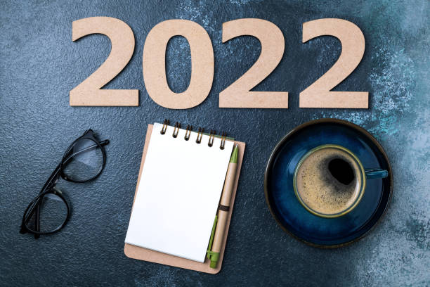 istock New year 2022 and notebook on desk. 2022 template with notebook, coffee cup, eyeglasses on blue table. Goals, planning, strategy, resolutions, business 1341506752