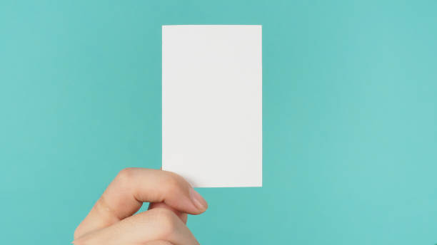 istock Empty space for text.Male hand holding white blank card isolated on mint green or Tiffany Blue background. 1341510204