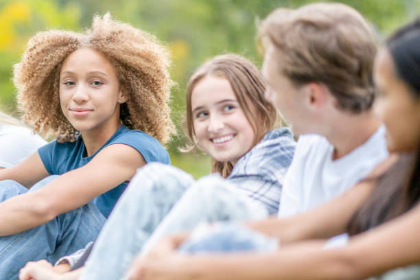 istock Multi-Ethnic High School Students Sitting in a Line Outside 1341510598