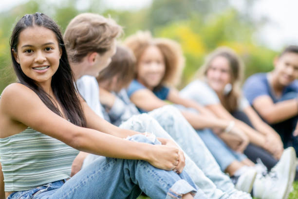 istock Multi-Ethnic High School Students Sitting in a Line Outside 1341510602