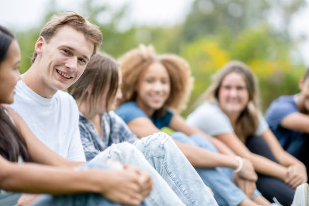 istock Multi-Ethnic High School Students Sitting in a Line Outside 1341510610