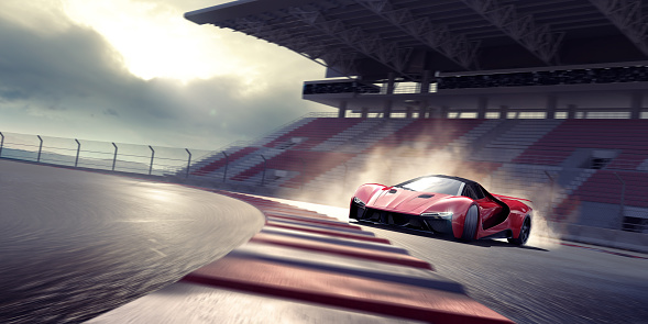 A generic red sports car viewed from the front and side as it drifts around a bend in a racetrack. The car is producing tire smoke from its back wheels and is moving fast with motion blur to the track, stand and wheels. With dramatic evening sunlight.