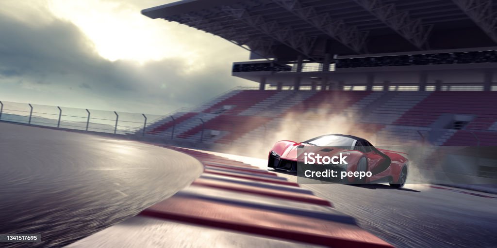 Red Sports Car Drifting Around A Bend On A Racetrack Near Empty Grandstand A generic red sports car viewed from the front and side as it drifts around a bend in a racetrack. The car is producing tire smoke from its back wheels and is moving fast with motion blur to the track, stand and wheels. With dramatic evening sunlight. Sports Track Stock Photo