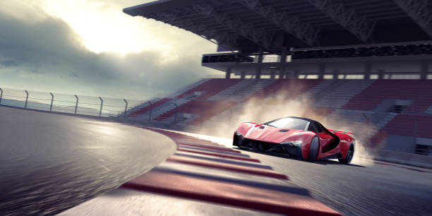Red Sports Car Drifting Around A Bend On A Racetrack Near Empty Grandstand A generic red sports car viewed from the front and side as it drifts around a bend in a racetrack. The car is producing tire smoke from its back wheels and is moving fast with motion blur to the track, stand and wheels. With dramatic evening sunlight. sports car stock pictures, royalty-free photos & images