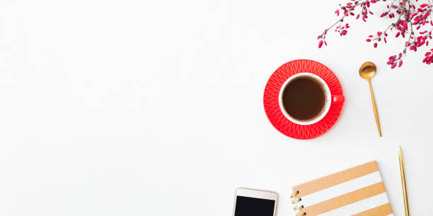 Flat lay composition with cup of coffee, branches with red berries and notebook on a white background