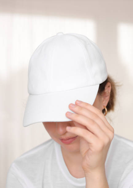 istock Female model wearing a white baseball cap. White cap mockup, template for picture, text or logo. Girl holding visor of cap. Free space, copy space. 1341523996