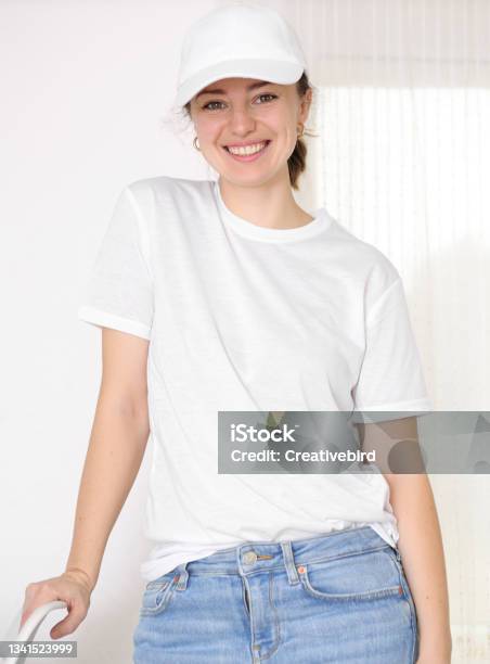 Female Model Wearing A White Tshirt And Baseball Cap White Cap And Tshirt Mockup Template For Picture Text Or Logo Smiling Attractive Girl Free Space Copy Space Stock Photo - Download Image Now