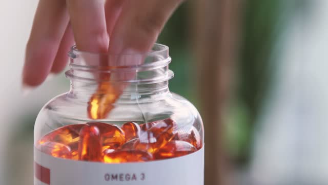 Close up of a person taking an Omega-3 fish oil capsule