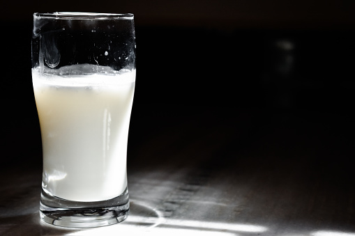 Glass of milk on table on black background with copy space